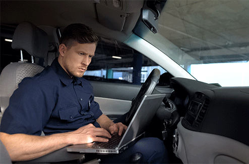 Un homme utilise son ordinateur portable dans sa voiture