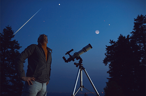 Un homme observe les étoiles filantes avec son télescope 
