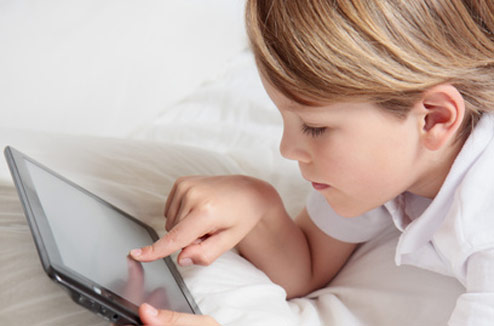 Un enfant qui lit une BD sur tablette tactile