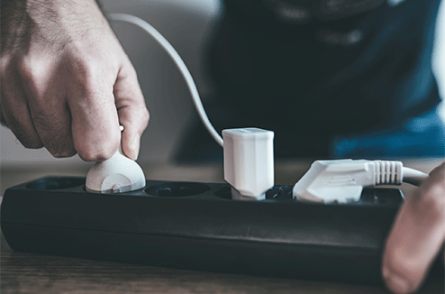 Une personne qui débranche un appareil électrique sur une multiprise