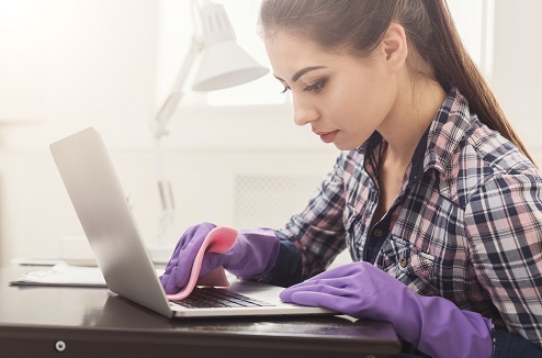 Jeune femme nettoyant son clavier d'ordinateur