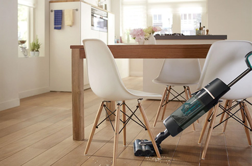L'AquaTrio de Philips en train d'être passé sous une table sur un sol sale