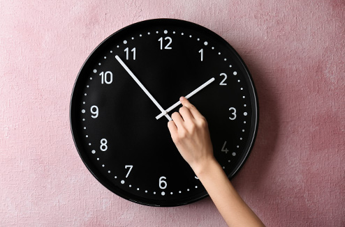 Le changement d'heure est là ! une femme changeant la place des aiguilles d'une horloge