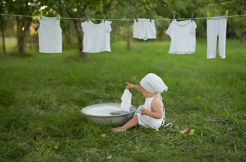Un bebe assis sur l'herbe fait sa lessive