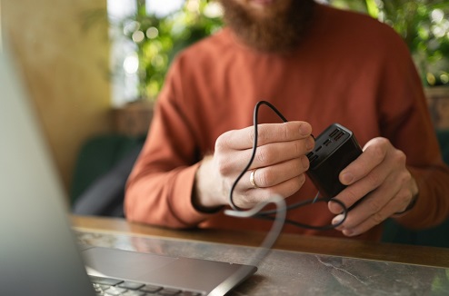 Un homme barbu branche son PC sur uen batterie externe
