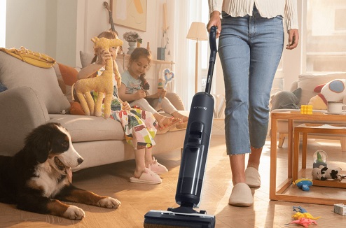 Jeune femme utilise l'aspirateur Tineco Extreme dans un salon avec un chien et deux enfants