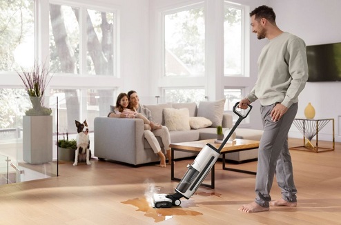 Homme passe un aspirateur balai laveur sa famille et son chien sont à côté