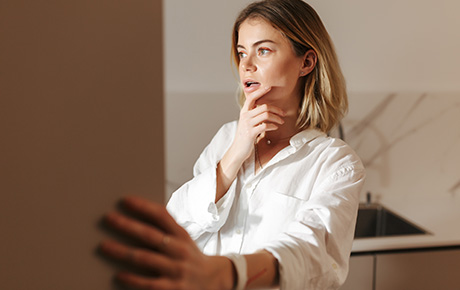 Une femme réfléchissant devant un frigo ouvert