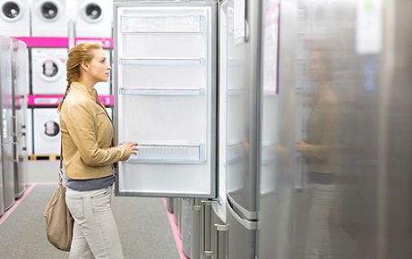 Une femme ouvre un frigo dans un magasin de Gros Electromenager