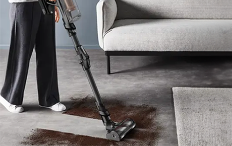 Une femme passant le X-Force Flex 14.80 sur un sol moquette plein de terre