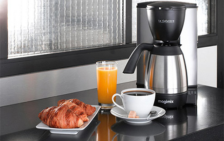Un petit déjeuner avec une tasse de café, un jus d'orange et des croissants