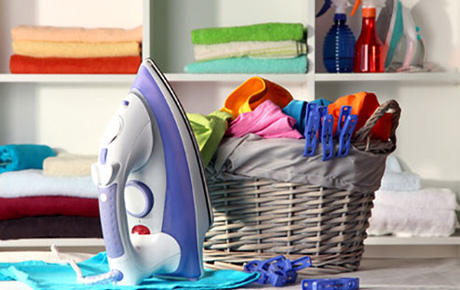 Un fer à repasser à coté d'un panier à linge