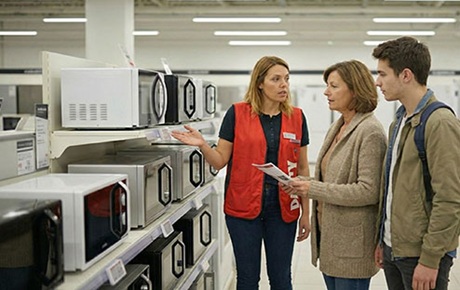 Une vendeuse Darty montre des micro-ondes à une femme et son fils 