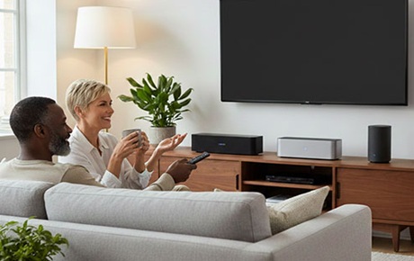 Un couple regarde une tv sous laquelle se trouvent plusieurs barres de son compactes