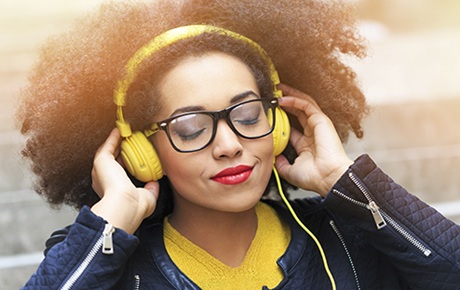 Une femme de couleur écoute un csque filaire jaune