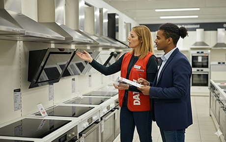 Une vendeuse Darty présente des hottes aspirantes à un homme jeune