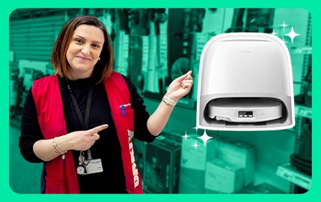 Une vendeuse Darty montre un aspirateur robot situé sur sa gauche