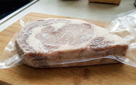 Une viande sous vide qui décongèle sur une planche à découper