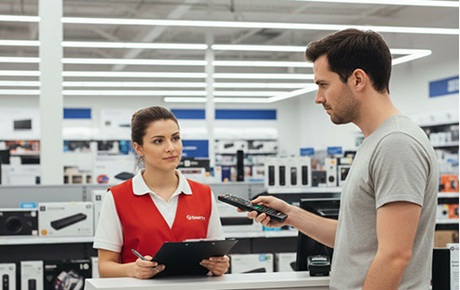 Une vendeuse Darty discute avec un client qui tient une télécommande