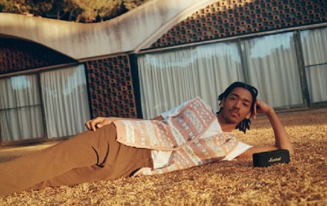 Un jeune homme allongé par terre écoute sa musique sur une enceinte Bluetooth