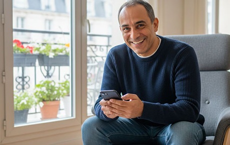 Un homme sourit en tenant un smartphone dans ses mains