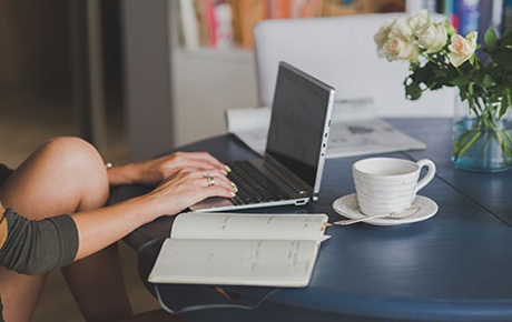 Une jeune femme utilise un pc portable posé sur une tbale 