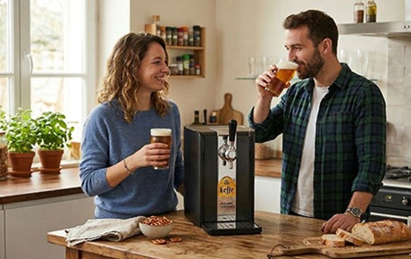 Un couple dans sa cuisine déguste de la biere tirée d'une tireuse