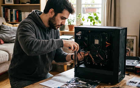 Un homme installant sa carte mère dans son PC dans son salon