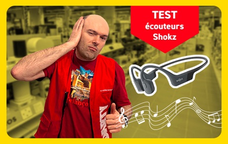 Un vendeur Darty fait le signe OK à côté d'écouteurs de marque Shockz