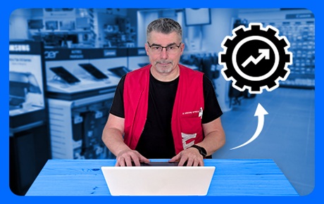 Un vendeur Darty assis à son bureau derrière un pc portable blanc