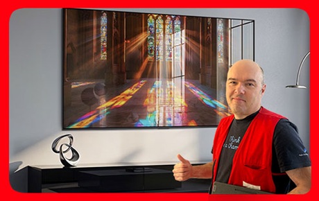 Un vendeur Darty fait le signe OK à côté d'un TV Samsung S99H