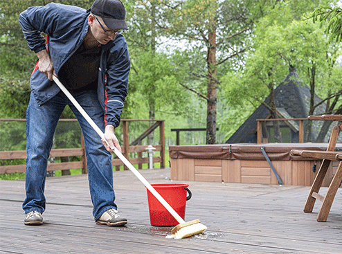 Un homme nettoie sa terrasse avec un balai