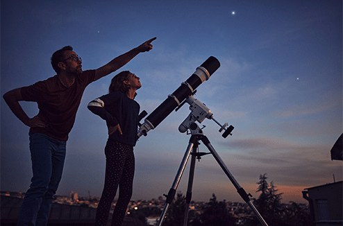 Un père et sa fille avec leur télescope, observant le ciel