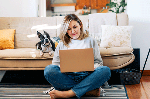 Une femme utilise son ordinateur devant son canapé