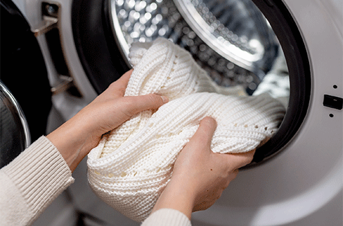 Une personne sort son linge de son lave-linge