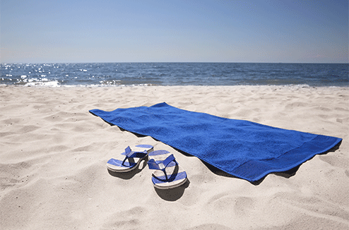 Une serviette de plage dans le sable, au bord de la mer