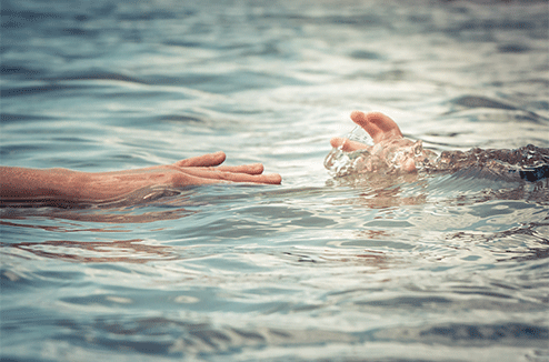 Une personne attrape le bras d'un enfant dans l'eau 