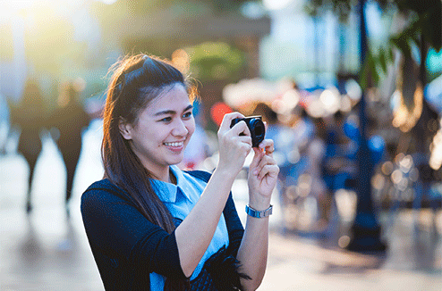 Une femme prenant une photo avec son compact dans la rue