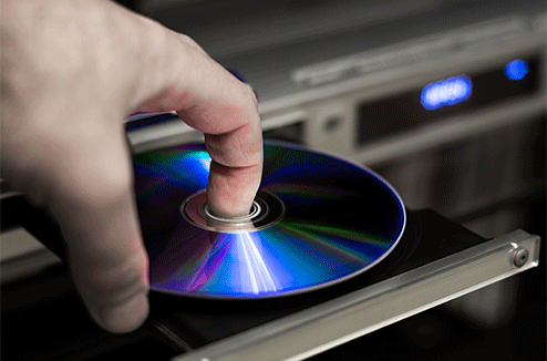 Une personne insère un DVD dans un lecteur de disque