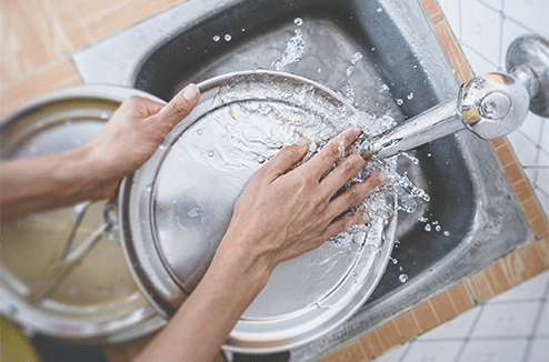 Une femme lave de la vaisselle à la main