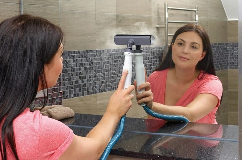 femme nettoyant un miroir avec un nettoyeur vapeur