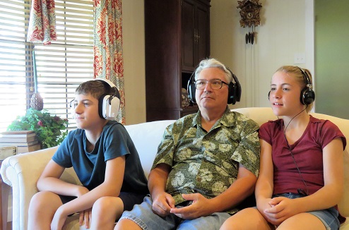 Famille regardant la TV avec des casques audio sur la tête
