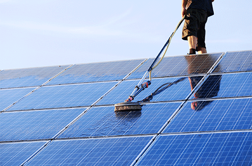 Un homme nettoie des panneaux solaires sur un toit