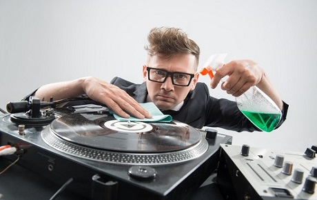 Un homme type hipster est en train de nettoyer une platine vinyle
