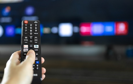 Une main dirige une télécommande vers un TV Samsung