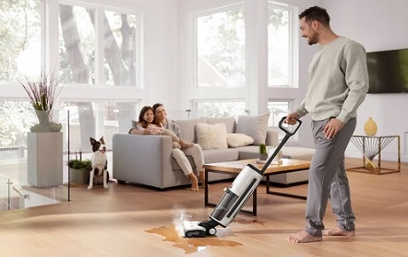 Homme passe un aspirateur balai laveur sa famille et son chien sont à côté