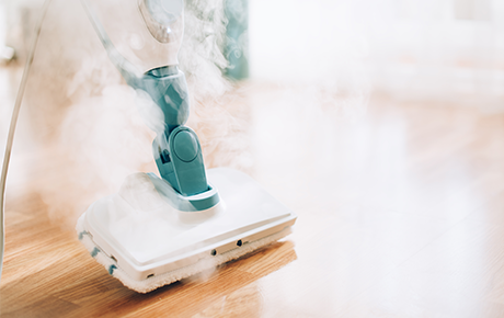 Une tête de nettoyeur vapeur sur un parquet en bois plein de vapeur