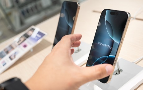 Main d'homme prend un iPhone 16 Pro sur un comptoir de magasin