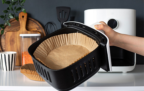 Image d'un airfryer avec un papier cuisson à l'intérieur
