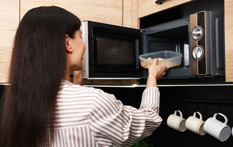 Une femme réchauffant son repas au micro-ondes